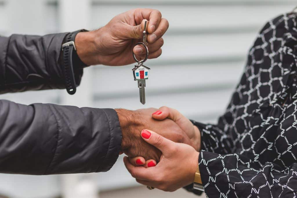 A mortgage loan officer handing the keys to a new homeowner.