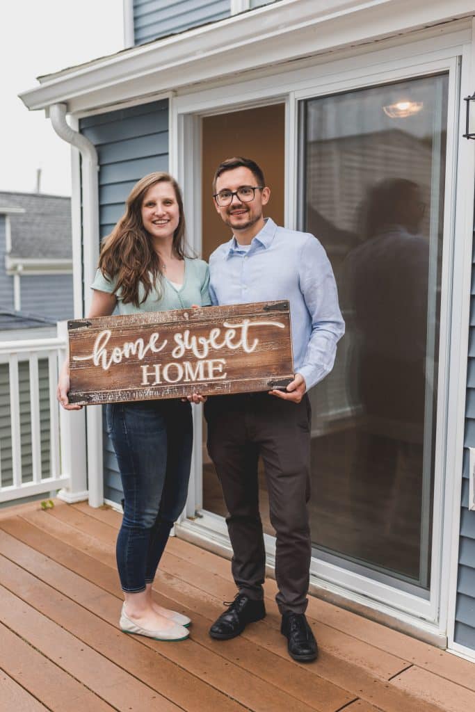 A family holding a home sweet home sign on the patio of a home they purchased with an FHA loan.